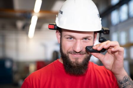 Service / Instandhaltung - Ein Monteur, mit Helm und Remotebrille lächelt in die Kamera